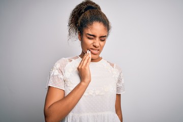 Fototapeta na wymiar Young beautiful african american girl wearing casual t-shirt standing over white background touching mouth with hand with painful expression because of toothache or dental illness on teeth. Dentist