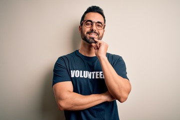 Handsome man with beard wearing t-shirt with volunteer message over white background looking...
