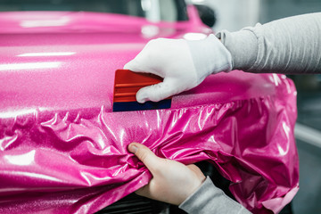 Car wrapping specialist putting vinyl foil or film on car. Selective focus.