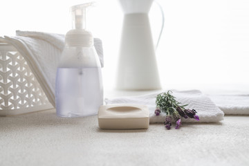 White cotton towels, soap, and lavender flowers on white background, copy space for product display. Aromatherapy, spa concept