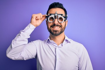 Young handsome optical man with beard wearing optometry glasses over purple background with a happy face standing and smiling with a confident smile showing teeth