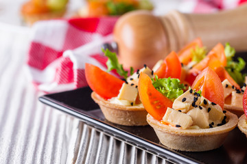 delicious snack tartlets on rustic wooden background