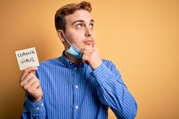 Young man wearing medical security mas holding paper note reminder with coronavirus alert word...