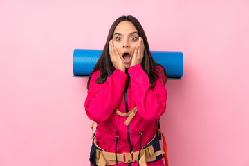 Young mountaineer girl with a big backpack over isolated pink background with surprise and shocked facial expression