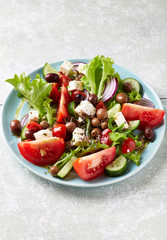 Healthy and tasty salad with feta cheese, various tomatoes, olives, cucumber, onion and lettuce.	