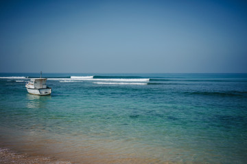 Wave on Hikkaduwa Beach with diving boat
