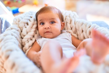 Beautiful infant happy at kindergarten around colorful toys lying inside crib