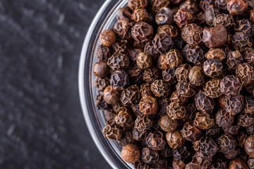 aromatic black pepper on a dark stone background
