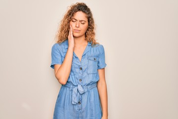 Young beautiful woman with blue eyes wearing casual denim dress over white background touching mouth with hand with painful expression because of toothache or dental illness on teeth. Dentist