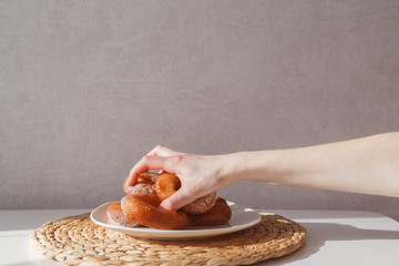 Glutton girl takes donuts from a plate one by one. Girls hand and plate with donuts