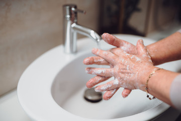 Close up details of woman scrubing and washing hands at home . Hygiene and body cleaning concept detail, pandemic, coronavirus concept