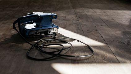 A machine for grinding wood on a wooden floor. Repairs.