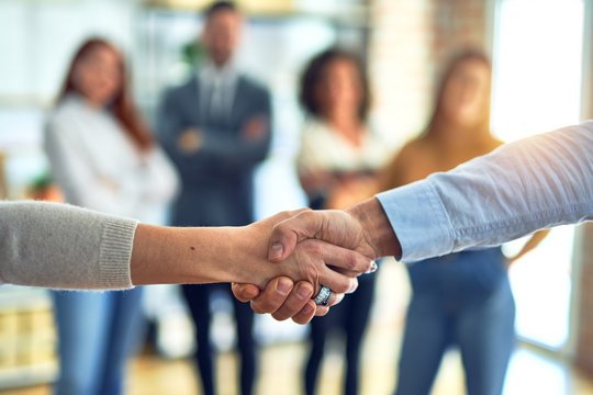 Group of business workers standing together shaking hands at the office