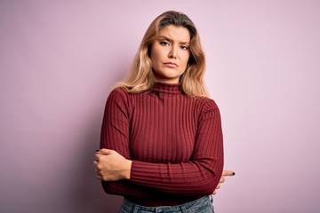 Fototapeta premium Young beautiful blonde woman wearing casual sweater over isolated pink background skeptic and nervous, disapproving expression on face with crossed arms. Negative person.