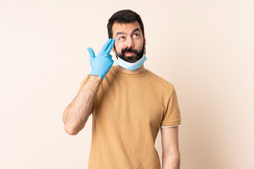 Caucasian man with beard protecting from the coronavirus with a mask and gloves over isolated background with problems making suicide gesture