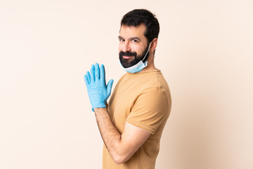 Caucasian man with beard protecting from the coronavirus with a mask and gloves over isolated...