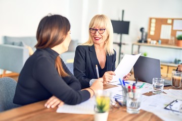 Two beautiful bussineswomen smiling happy. Working together with smile on face speaking at the office