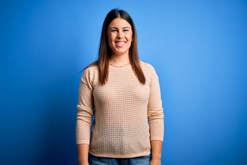 Young beautiful woman wearing casual sweater over blue background with a happy and cool smile on face. Lucky person.