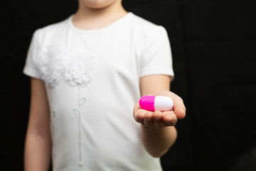 Girl holds a toy pill.