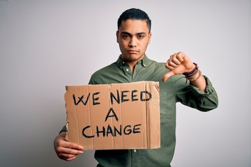 Young brazilian activist man asking for change holding banner over white background with angry...