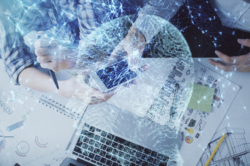 Double exposure of man and woman working together holding and using a mobile device and brain hologram drawing.