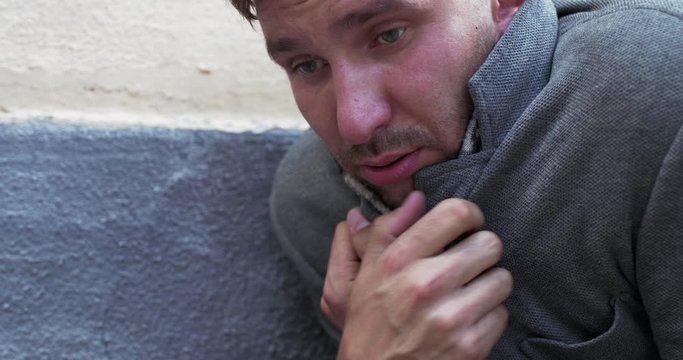 Portrait of man trembling from strong fever and wipes his forehead near building