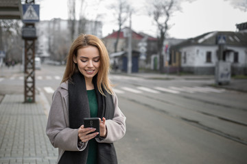 Fototapeta premium Girl writes message at smartphone on tram stop.