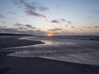 Sunset over Baltic Sea, empty beach, waves on the sea. Shot during windy weather. Leba, Poland.