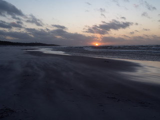 Sunset over Baltic Sea, empty beach, waves on the sea. Shot during windy weather. Leba, Poland.