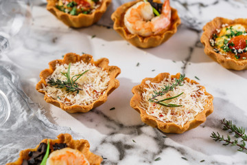 Delicious appetizers in tart with baked egg with cheese on marble banquet table. Catering food, canape and snacks, close up