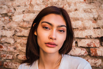 Young latin woman against brick wall.