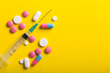 Assorted pharmaceutical medicine pills, tablets and capsules. Yellow background.