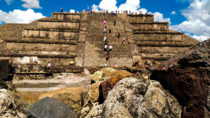 Rocks of the ancient pre-Columbian city and in the  Rocks of the ancient pre-Columbian city and in the background tourists climbing the pyramid with a blur technique.