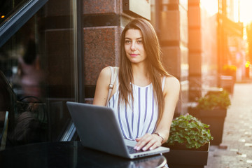 Young pretty woman in street cafe with tablet laptop