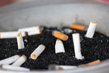 Cigarette butts in ashtray. Selective focus. Bokeh effect.