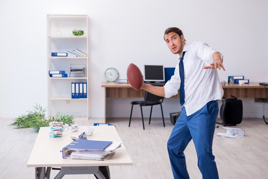 Young Male Employee Throwing Rugby Ball In The Office