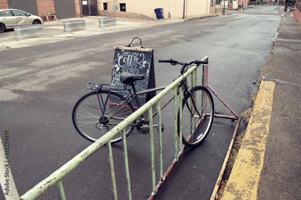 Wall mural Bicycle parked at railing in front of coffee sign