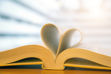 Book  in heart shape on desk at library for reading education learning or lifestyle love to read and february valentine day concepts.