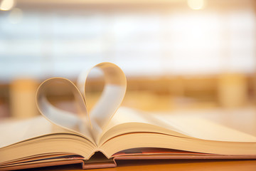 Book  in heart shape on desk at library for reading education learning or lifestyle love to read and february valentine day concepts.