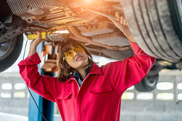 Obraz na płótnie Canvas Woman Mechanic Examining Under the Car at the Repair Garage.