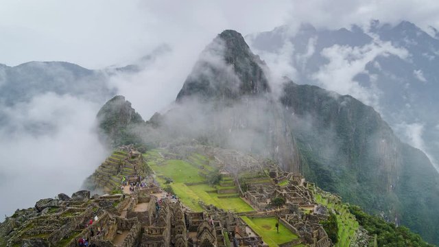 Zoom out time lapse view of mysterious Inca ruins of Machu Picchu shrouded in mist high in the Andes mountain range, Cusco Region, Peru.