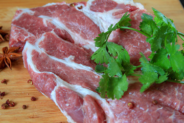 Pork on the bamboo cutting board with pepper and cilantro on the side