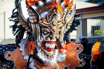 closeup man in motley masquerade mask passes by city street at dominican carnival