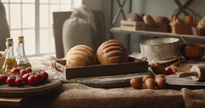 Fresh loafs of white bread in basket lying on table with eggs and table. Traditional components of bread recipe at bakery. Fresh loafs for breakfast - close up shot 4k footage