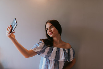 Naklejka premium A teenage girl with a phone takes selfies in her room