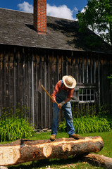 Man scoring timbre to hew a straight side on the log at Lang Pioneer Village
