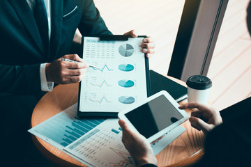 Managers are using tablets to analyze sales cost reports and explain summary reports to employees calculate and record summary information data in the office.