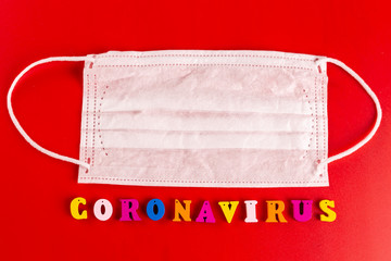 Coronavirus word made of colourful letters on red background . The inscription on medical protective mask coronavirus.