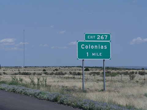 Directional sign on the road with directions to the exit for Colonias in New Mexico.