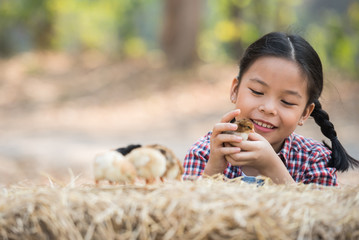 happy little girl with of small chickens sitting outdoor. portrait of an adorable little girl, preschool or school age, happy child holding a fluffy baby chicks with both hands and smiling..